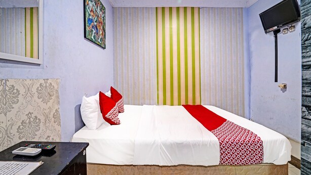 Habitación de hotel con cama, televisor, escritorio y calculadora, además de papel tapiz estampado.