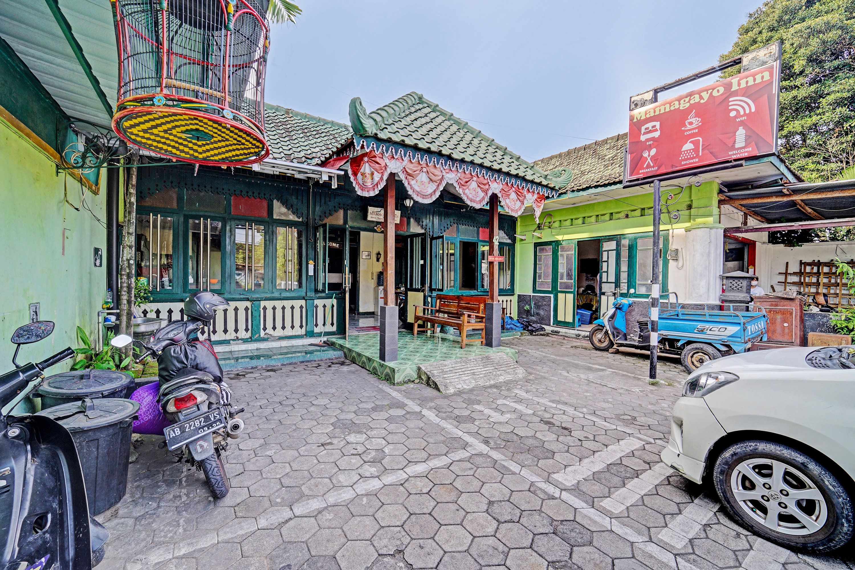 A traditional building with a tiled roof, a signboard for a bed and breakfast, and a parked scooter.