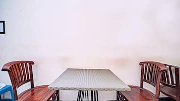 A square table with a woven top, flanked by two wooden chairs with curved backs.