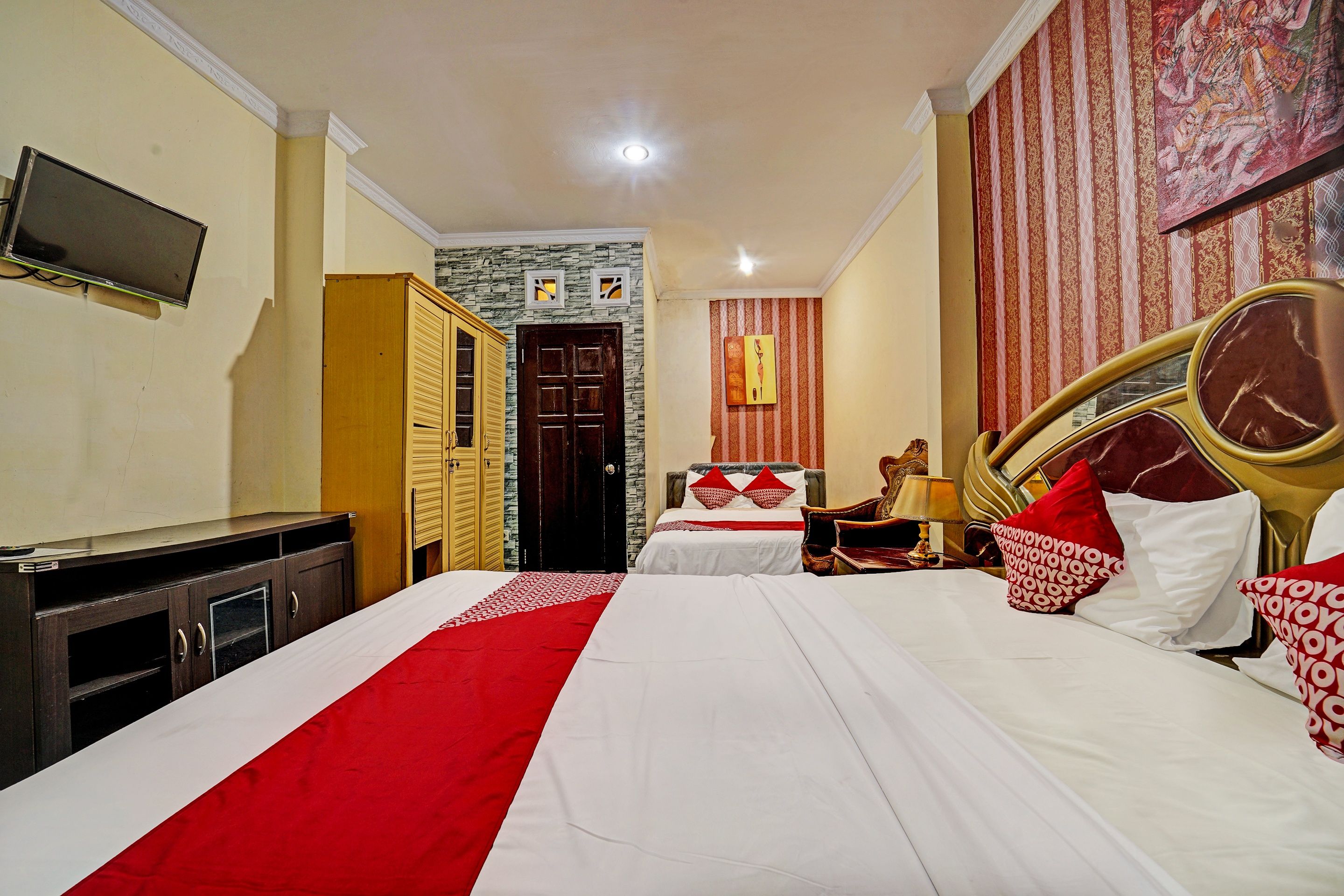 A hotel room with a bed, a desk, a wardrobe, a television, and a door.