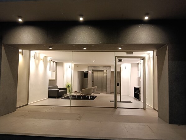 A modern interior with a reception desk, seating area, and a glass partition.