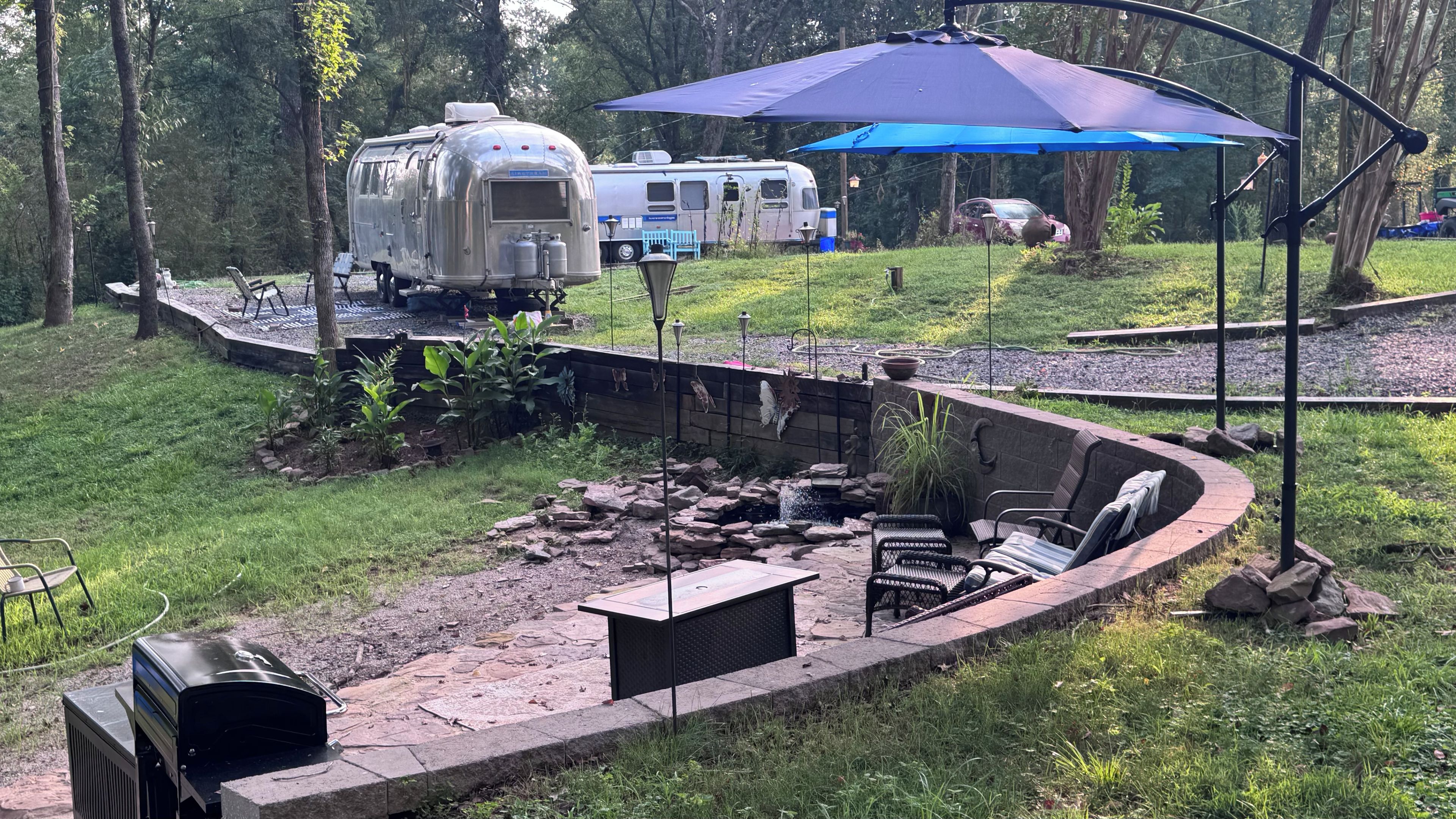 A camping area with a fire pit, seating, and a covered picnic table.