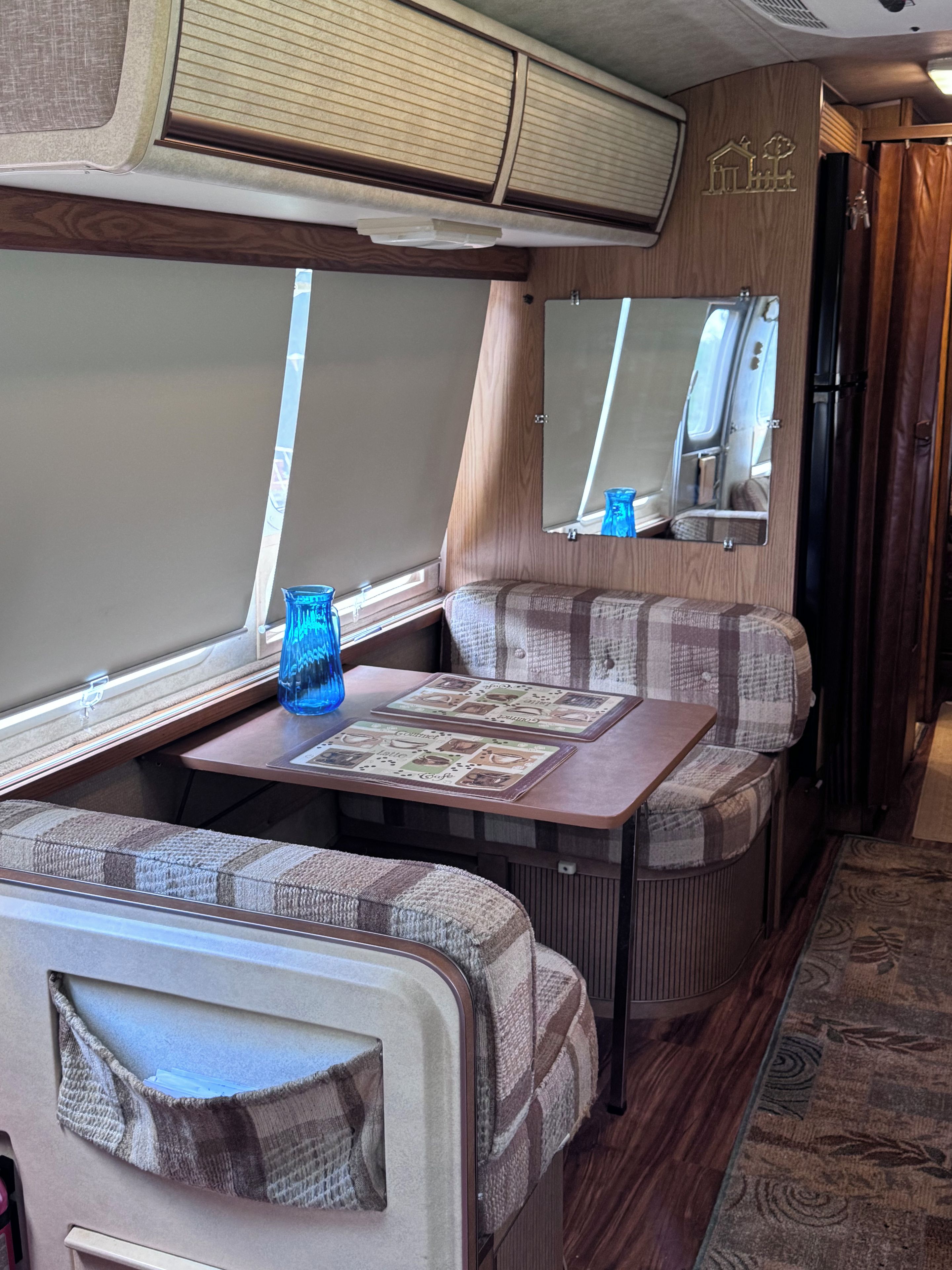 Interior compacto de autocaravana con kitchenette, comedor y zona de estar.