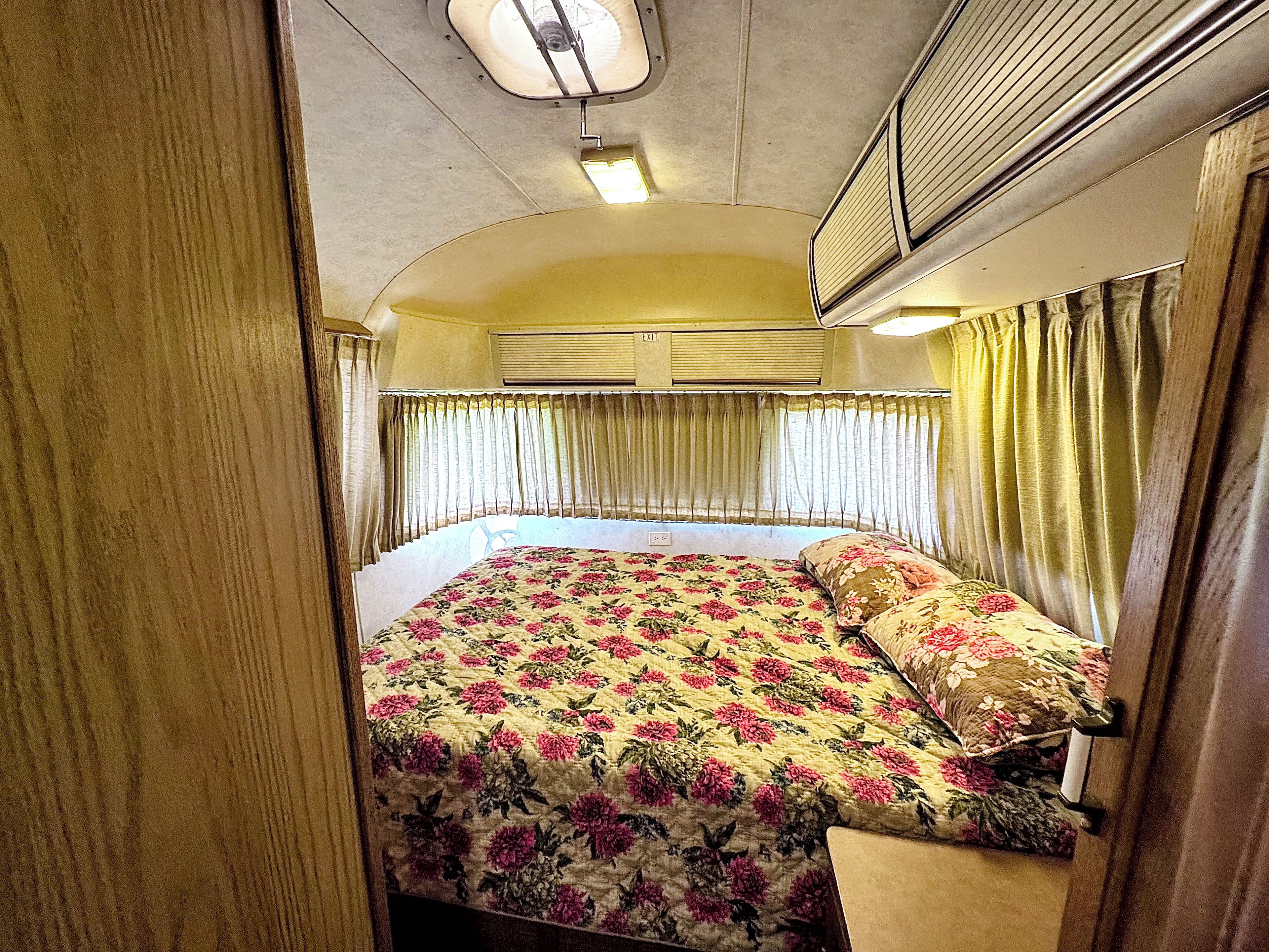 Habitación pequeña con cama, cortinas y equipo de aire acondicionado.