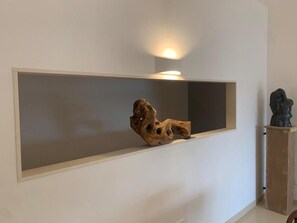 Estante en la pared con una escultura de madera y una pequeña escultura sobre un pedestal.