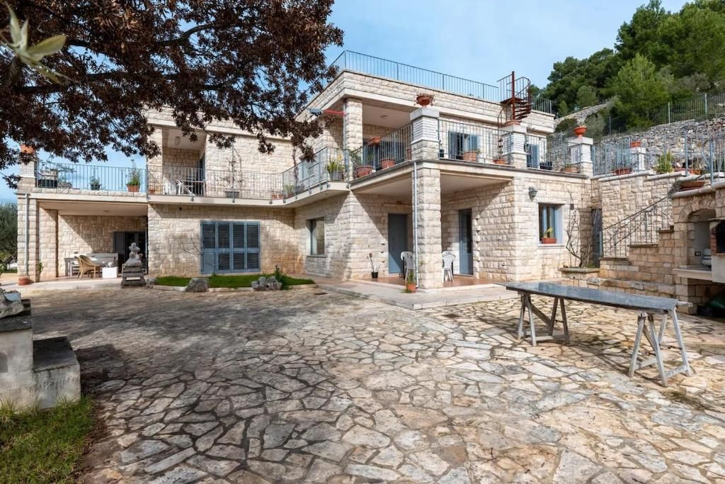 Un edificio de piedra con varios balcones, un patio con suelo de piedra y mobiliario exterior.