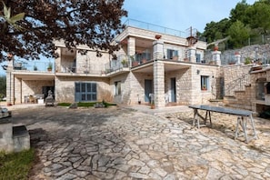 A stone building with multiple balconies, a courtyard with a stone floor, and outdoor furniture. - Oasidipacefasano  (Fasano)