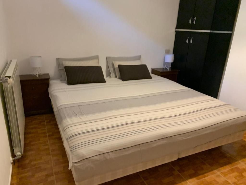 Un dormitorio con cama, dos mesitas de noche, un armario y un radiador.