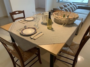 A dining table set with plates, cutlery, glasses, and a bottle of wine, with a basket of bread on the table. - Oasidipacefasano  (Fasano)