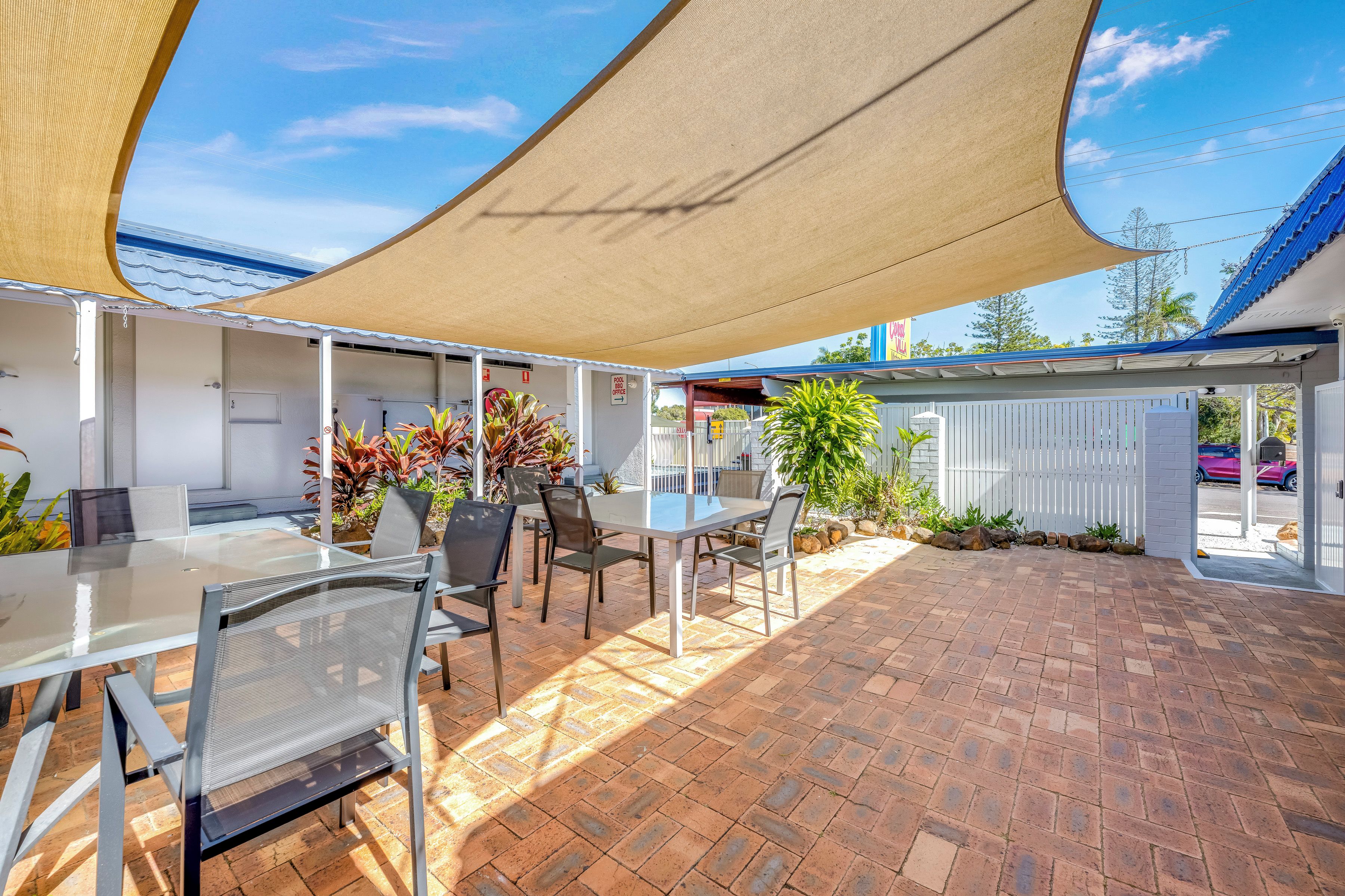 An outdoor patio area with a table and chairs, a pool office sign, and a covered seating area.