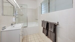 A modern bathroom with a glass shower enclosure, a white sink, and a bathtub. - Coral Villa Motel (Svensson Heights)