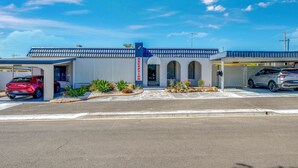 A building with a reception area, a covered parking section, and a garage. - Coral Villa Motel (Svensson Heights)