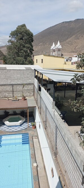 A rooftop pool area with a view of a hill and a church.