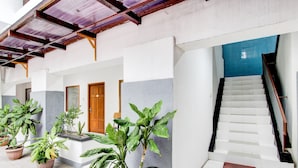 A building with a covered walkway, potted plants, and a staircase. - Hotel O Mamagayo Inn (Yogyakarta)