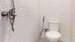 A bathroom with a white toilet, a shower with a hose, and a wall-mounted faucet. - Hotel O Mamagayo Inn (Yogyakarta)