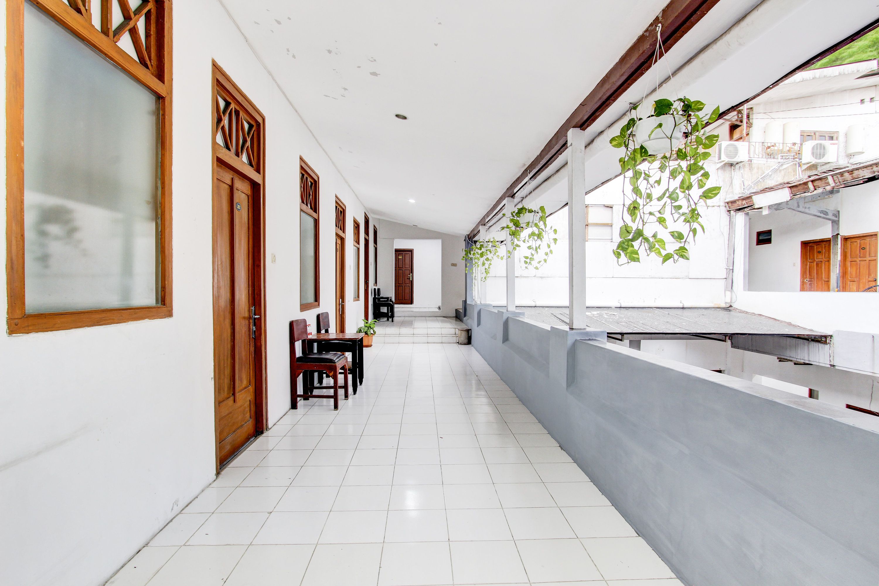 Un pasillo con puertas de madera, un comedor con mesa y sillas, y plantas colgantes.