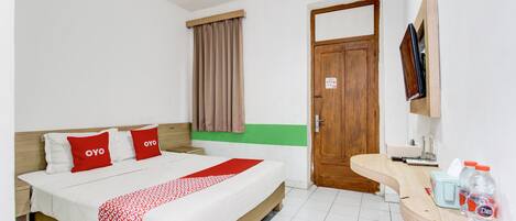 Une chambre d’hôtel avec un lit, une porte en bois, une petite table avec un téléviseur et une fenêtre avec des rideaux.