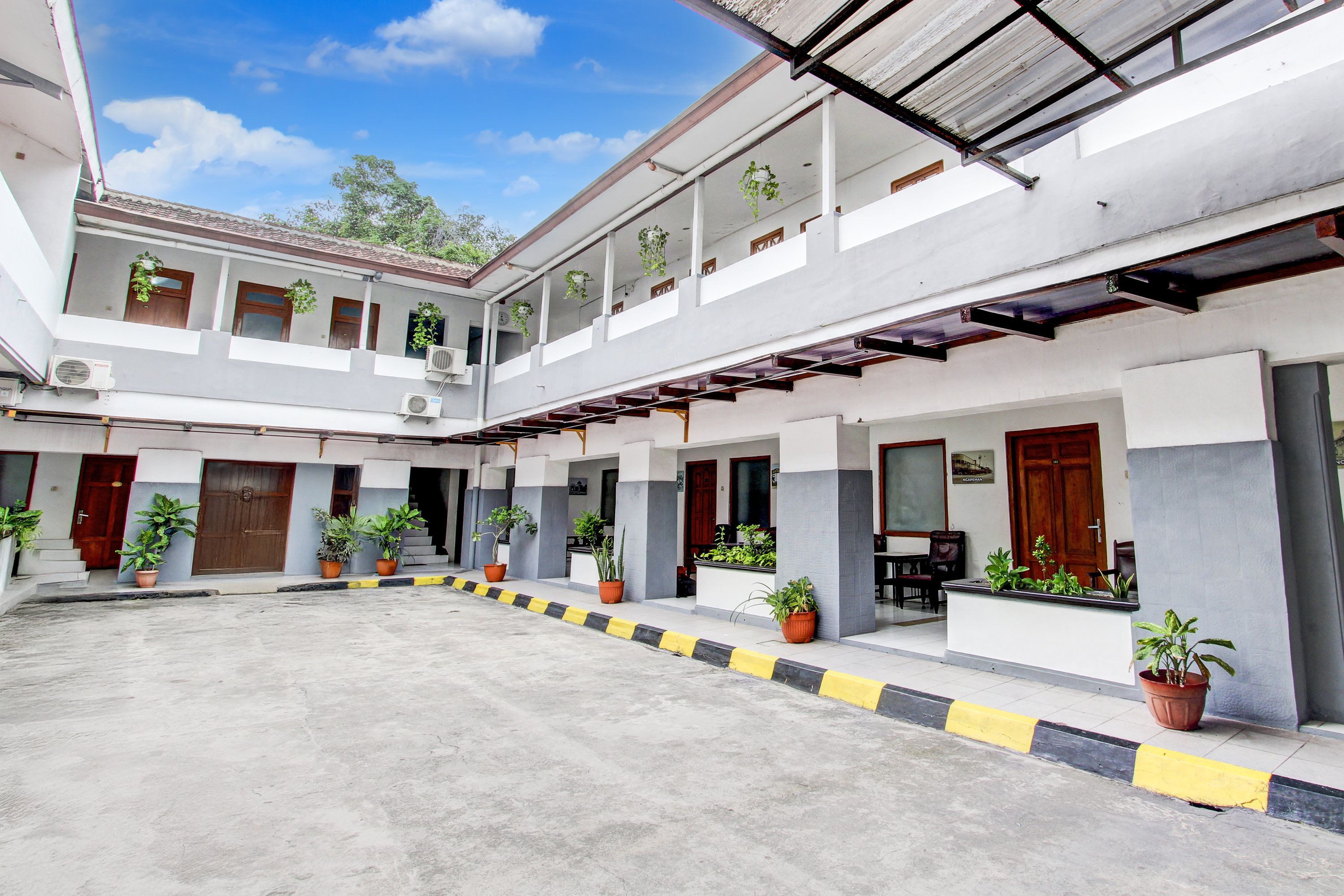 A courtyard with multiple rooms, potted plants, and a covered walkway.