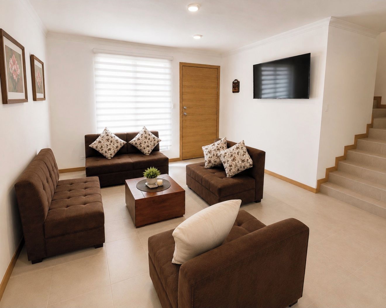 Sala de estar com sofá, mesa de centro com planta e televisão na parede.