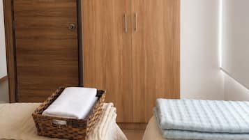A bedroom with two beds, a wooden wardrobe, and a window.