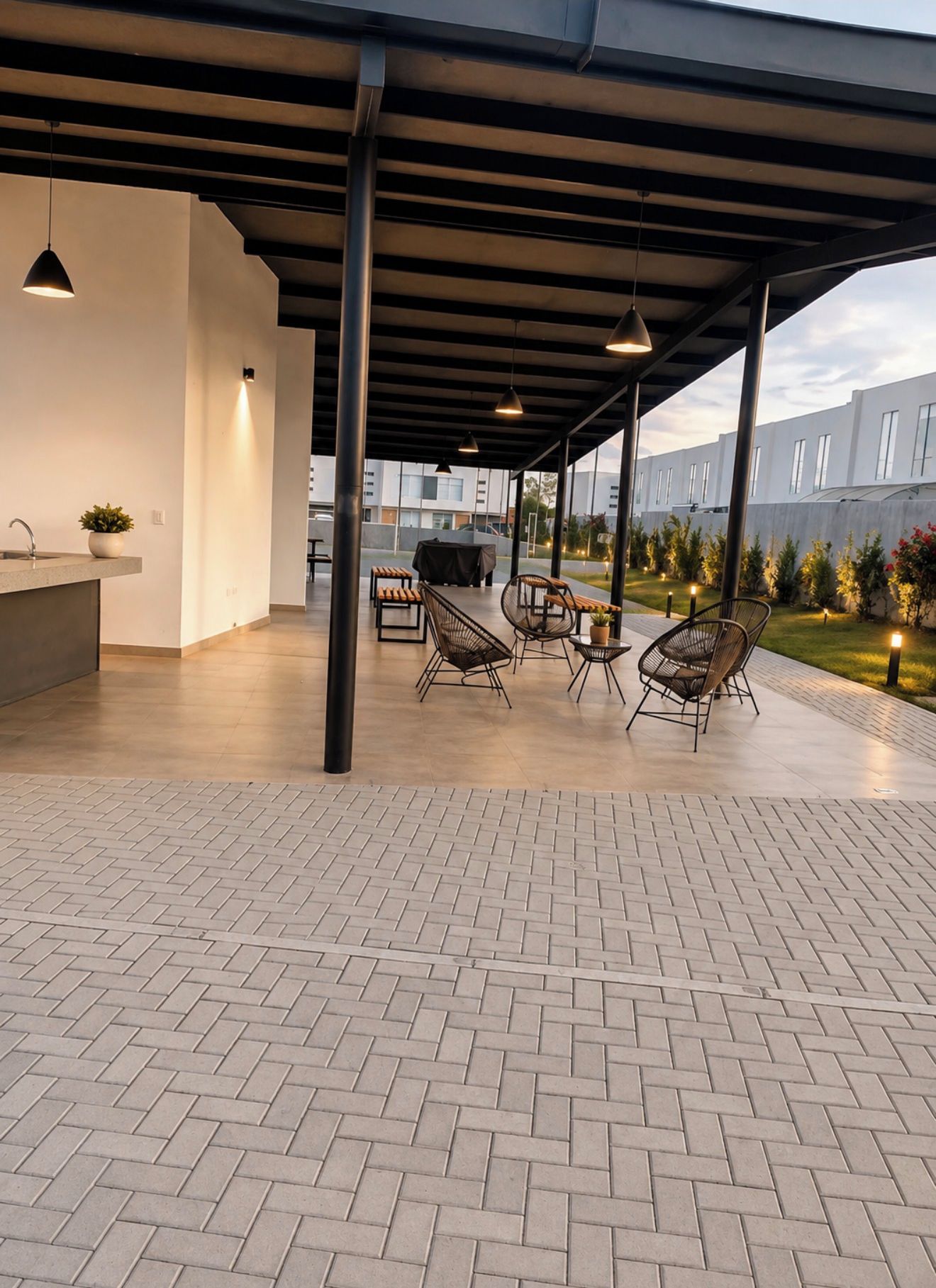 Un'area patio esterna con zona salotto coperta, un barbecue e vista su un edificio moderno sullo sfondo.