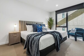 Une chambre à coucher moderne avec un lit, une table de chevet, une lampe et une chaise.