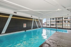 Ein Innenpool mit einem 'No Diving'-Schild, gefliesten Wänden und einem modernen Deckenbau.