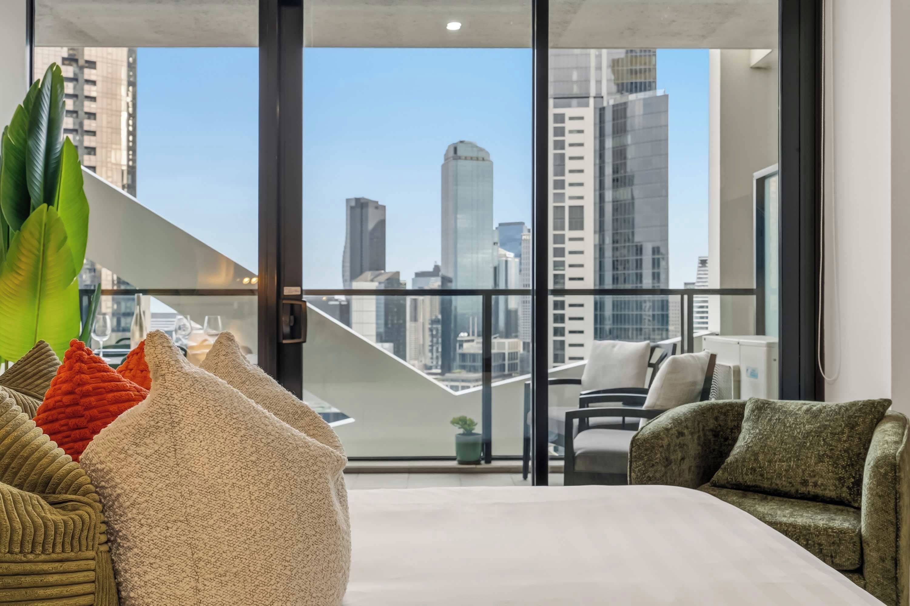 A modern living room with a city view, large windows, and a staircase.