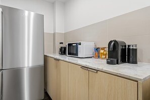 Eine moderne Küche mit Edelstahlgeräten, einer Mikrowelle, einer Kaffeemaschine und einem Wasserkocher auf der Arbeitsfläche.
