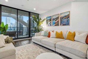 Un salon moderne avec une grande fenêtre, un canapé, une table basse et une plante en pot.
