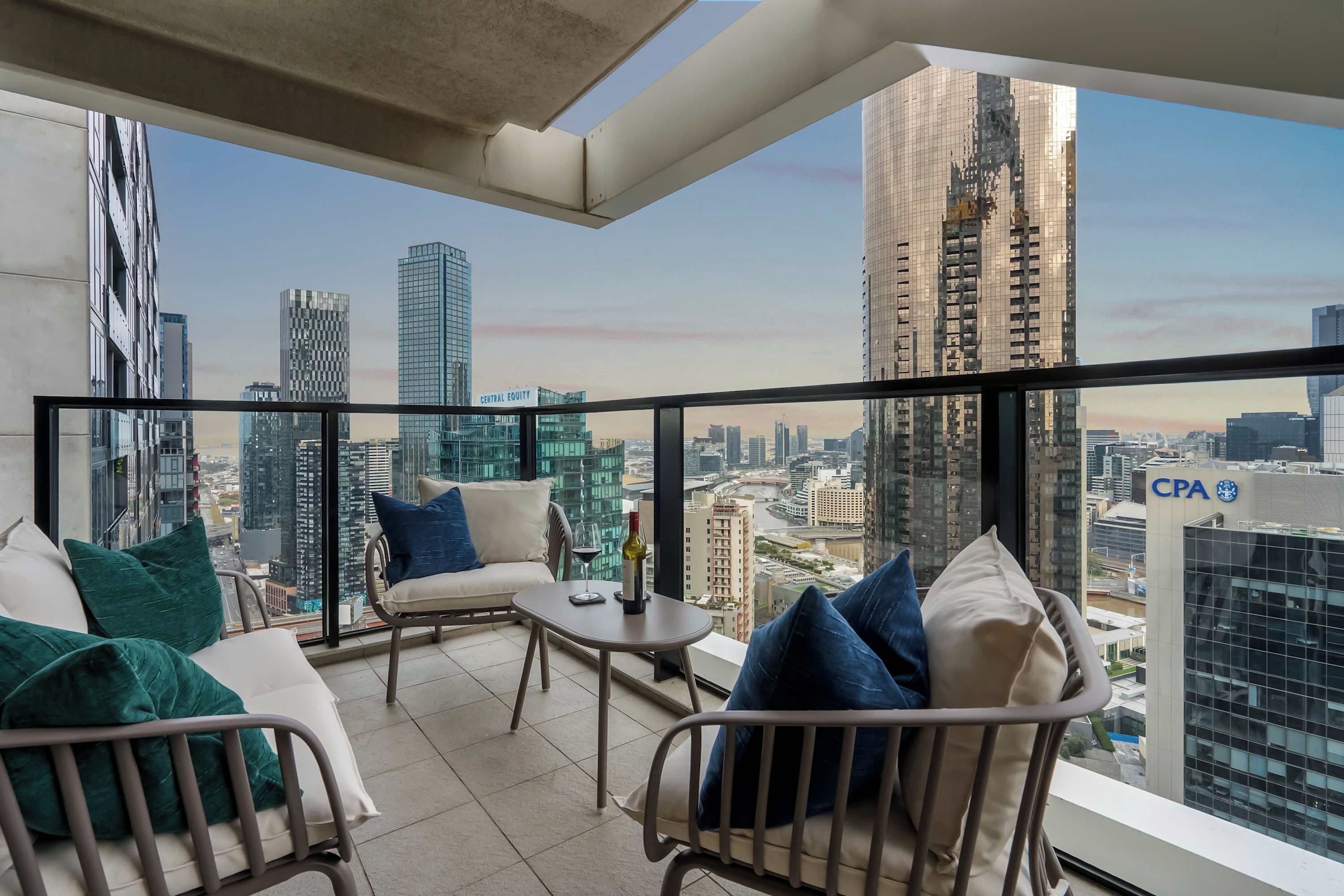 A balcony with a city view, furnished with a sofa, chairs, and a small table.