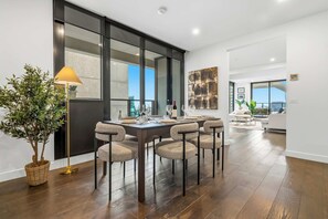 A modern dining area with a large table, chairs, and a potted plant. - 36th Floor Luxury 2BR City Views Pool & 2 Cars (Southbank)