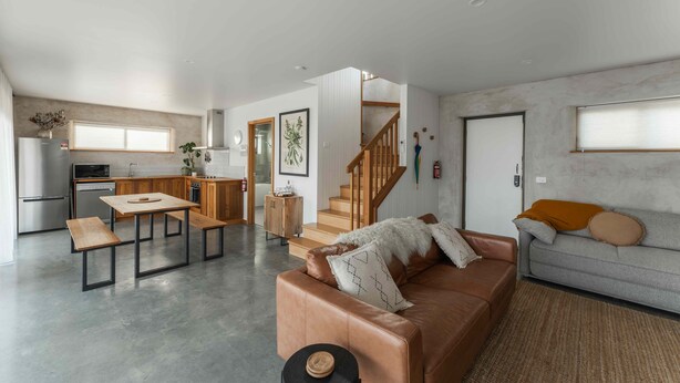 Un espace de vie moderne comprenant une cuisine, un coin repas et un escalier menant à un niveau supérieur.