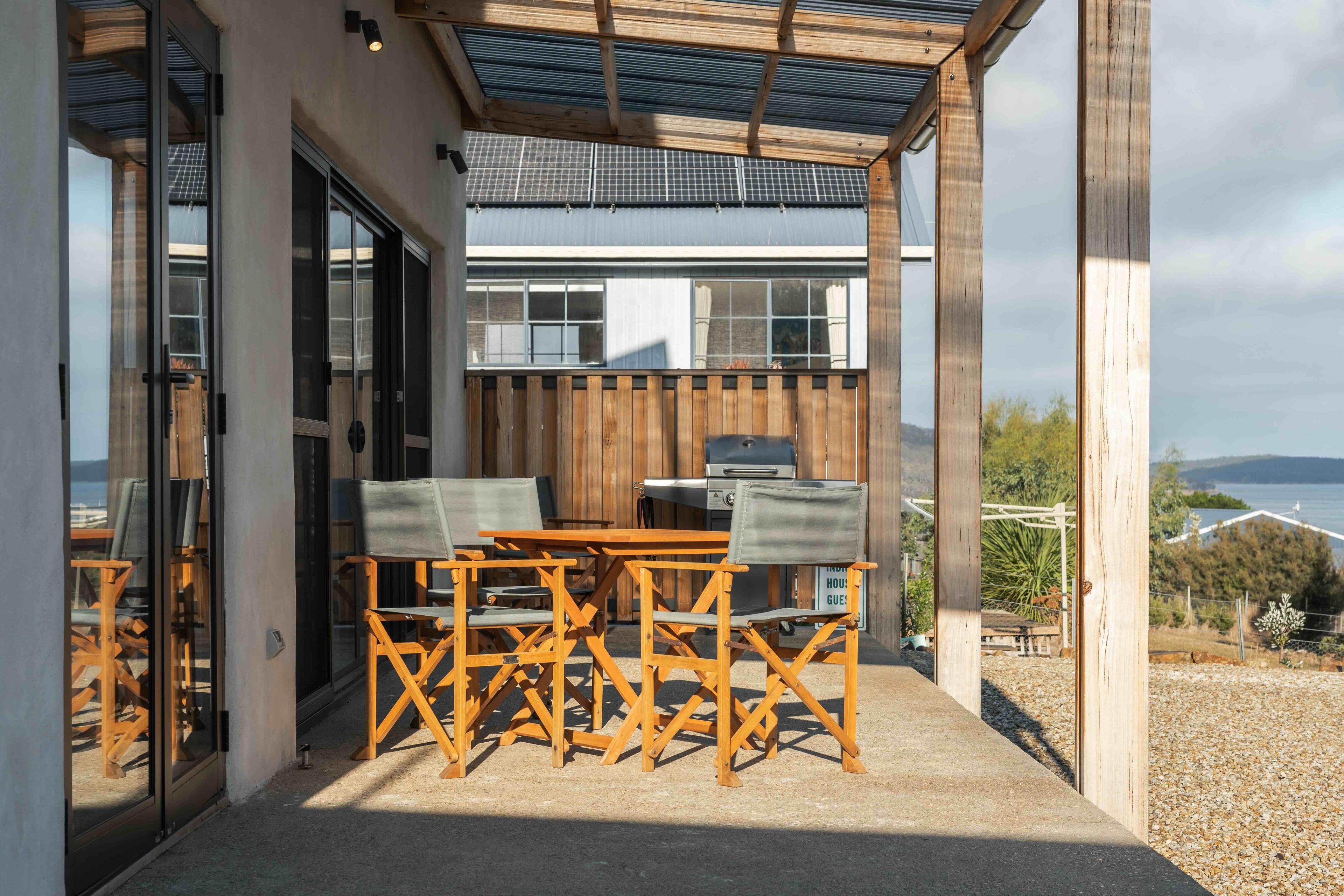 Un espace extérieur abrité, avec une table et des chaises, un barbecue et une vue sur le paysage.