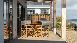 Un espace extérieur abrité, avec une table et des chaises, un barbecue et une vue sur le paysage.