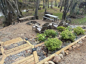 Um camping com mesas de piquenique, cadeiras e lareira.