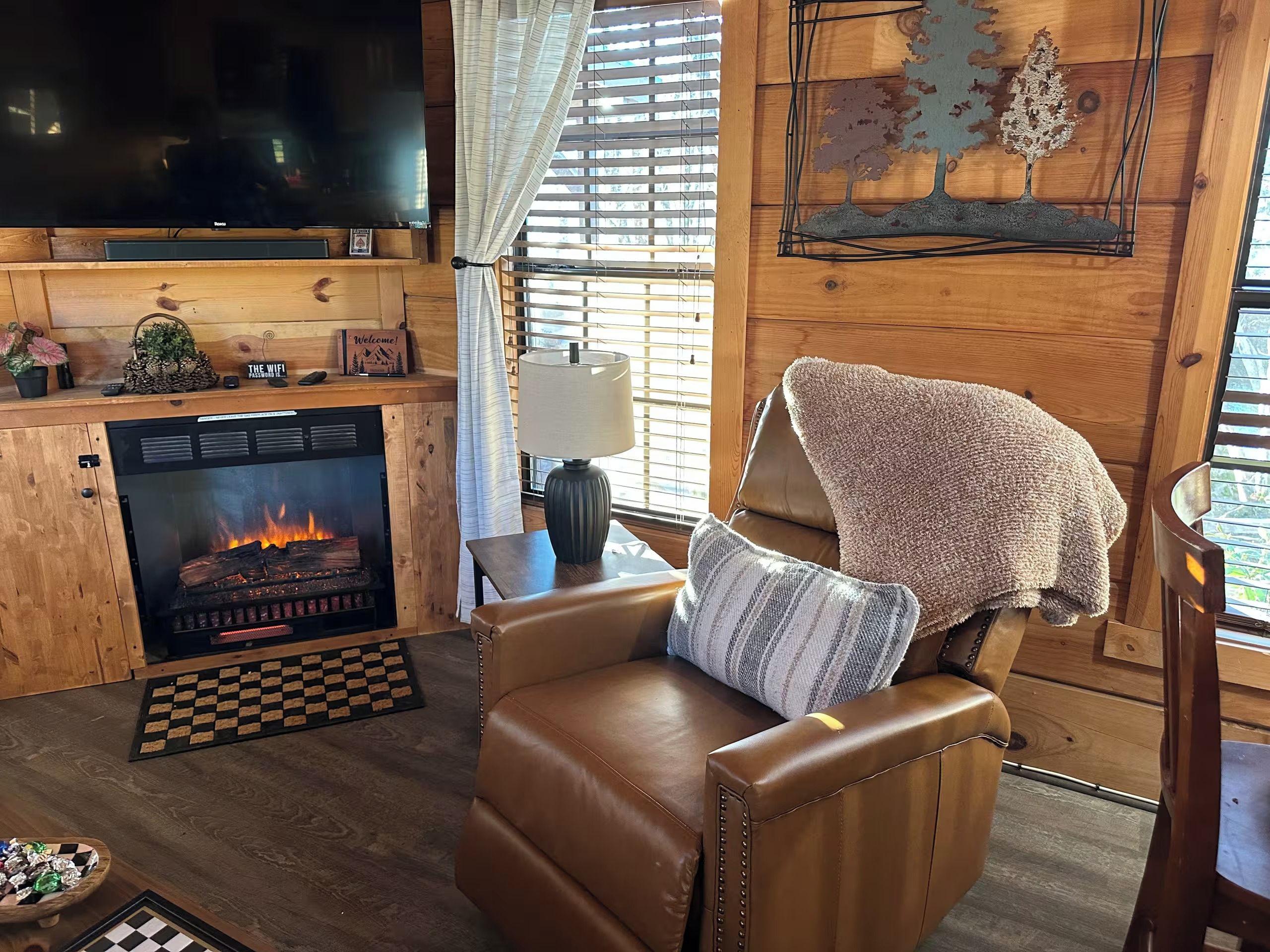 A cozy living room with a fireplace, leather sofa, and a flat-screen TV.