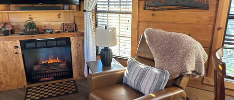 A cozy living room with a fireplace, leather sofa, and a flat-screen TV.
