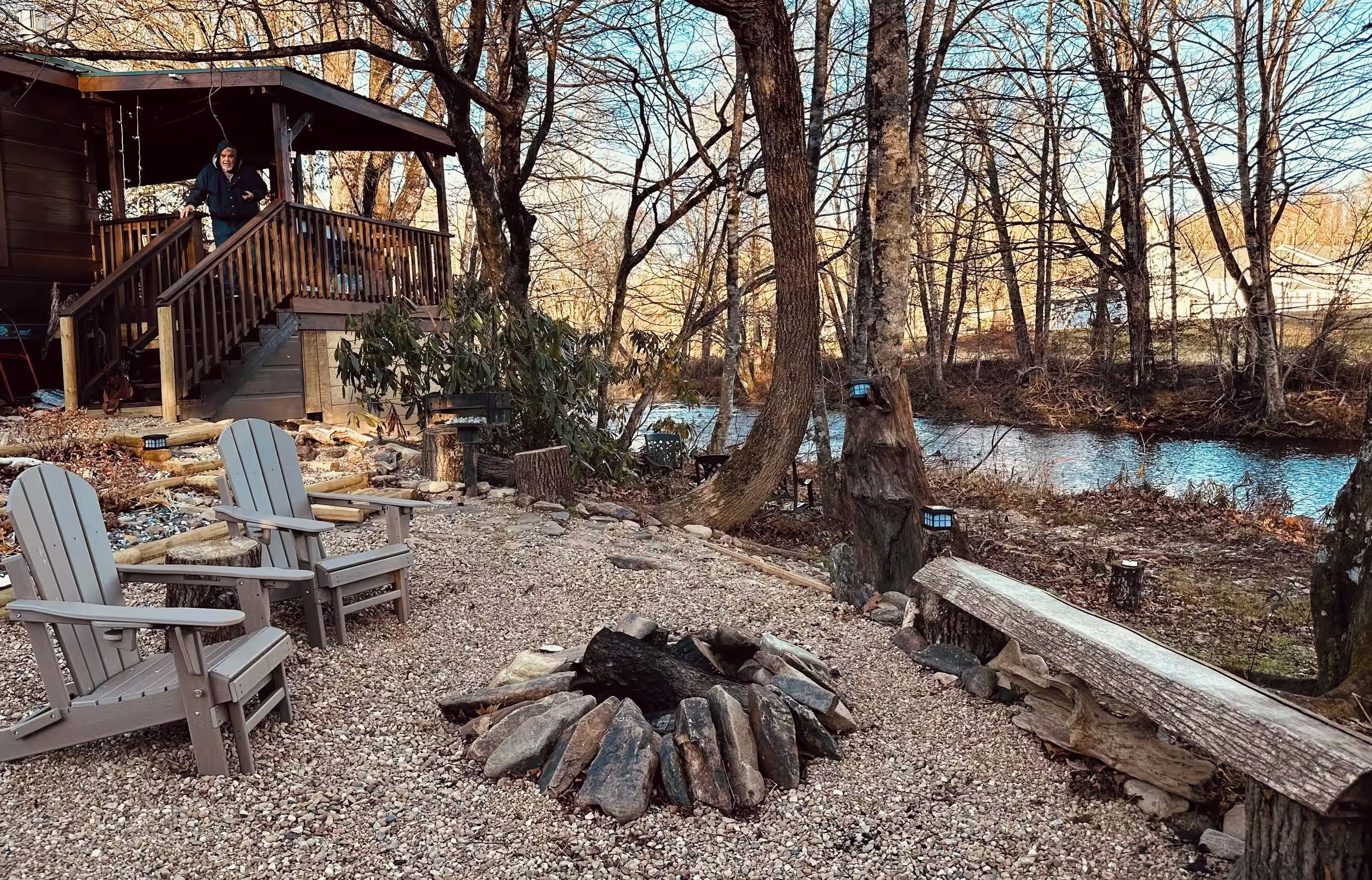 Une cabane avec une terrasse, un foyer et des chaises.