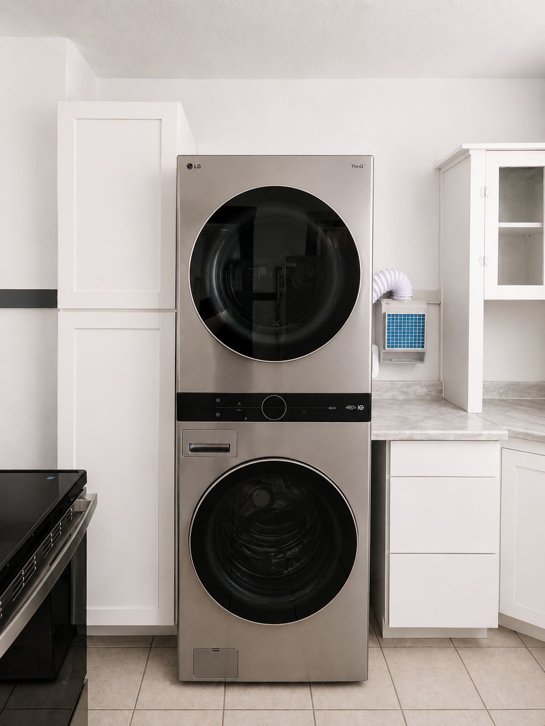 Cocina compacta y moderna con lavadora y secadora integradas, muebles blancos y una pequeña encimera.