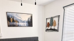 Ett sovrum med en säng, en målning som föreställer en skog och en väggdekoration.
