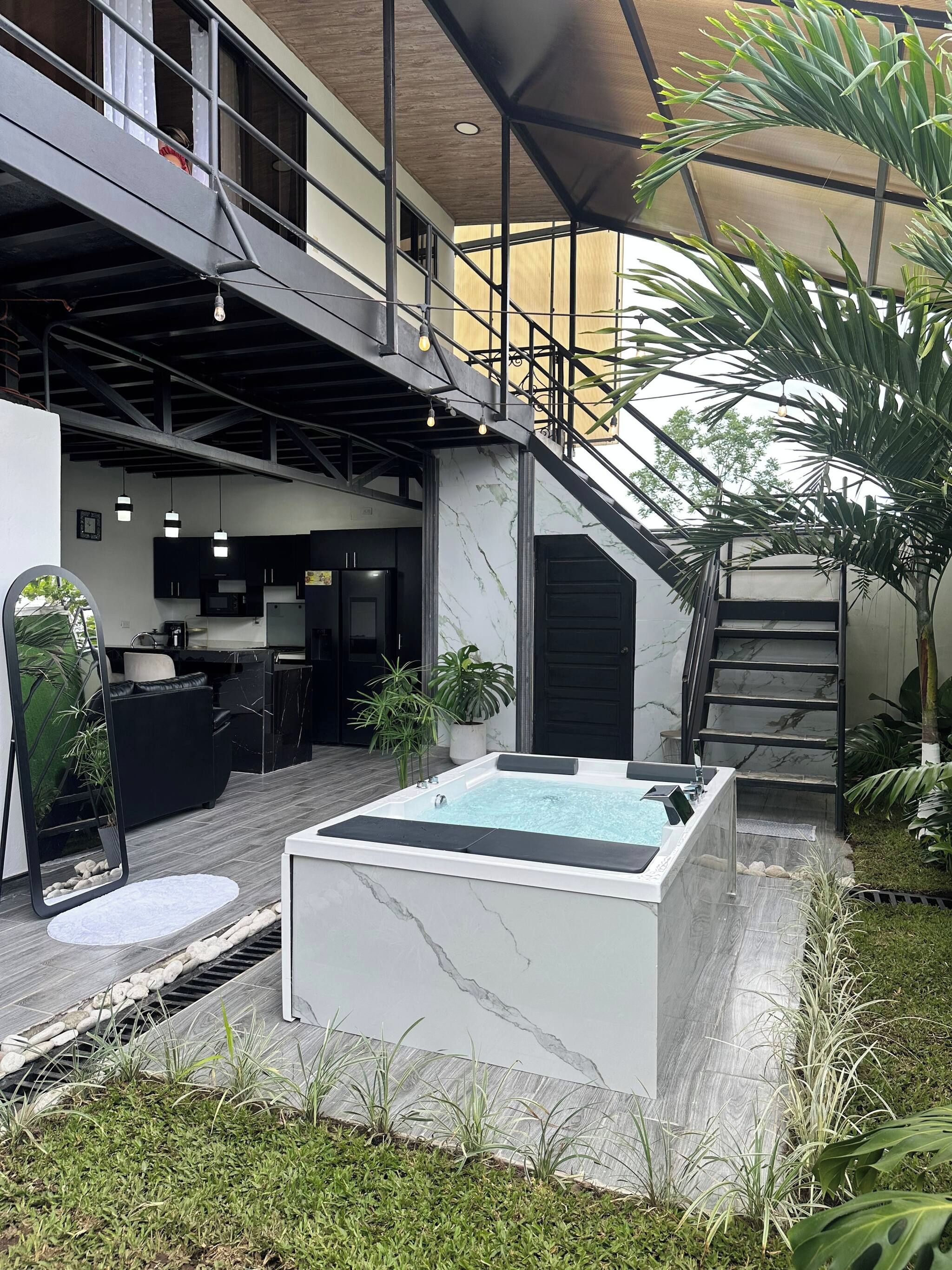 Un espacio exterior moderno con un jacuzzi, una escalera y una zona de cocina.
