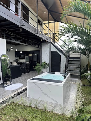 Un espacio exterior moderno con un jacuzzi, una escalera y una zona de cocina.