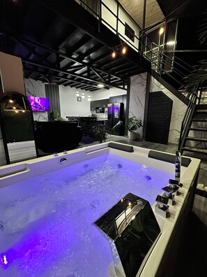 A modern interior with a large hot tub, a staircase, and a kitchen area. - Betandy Apartment Jacuzzi (Rita)