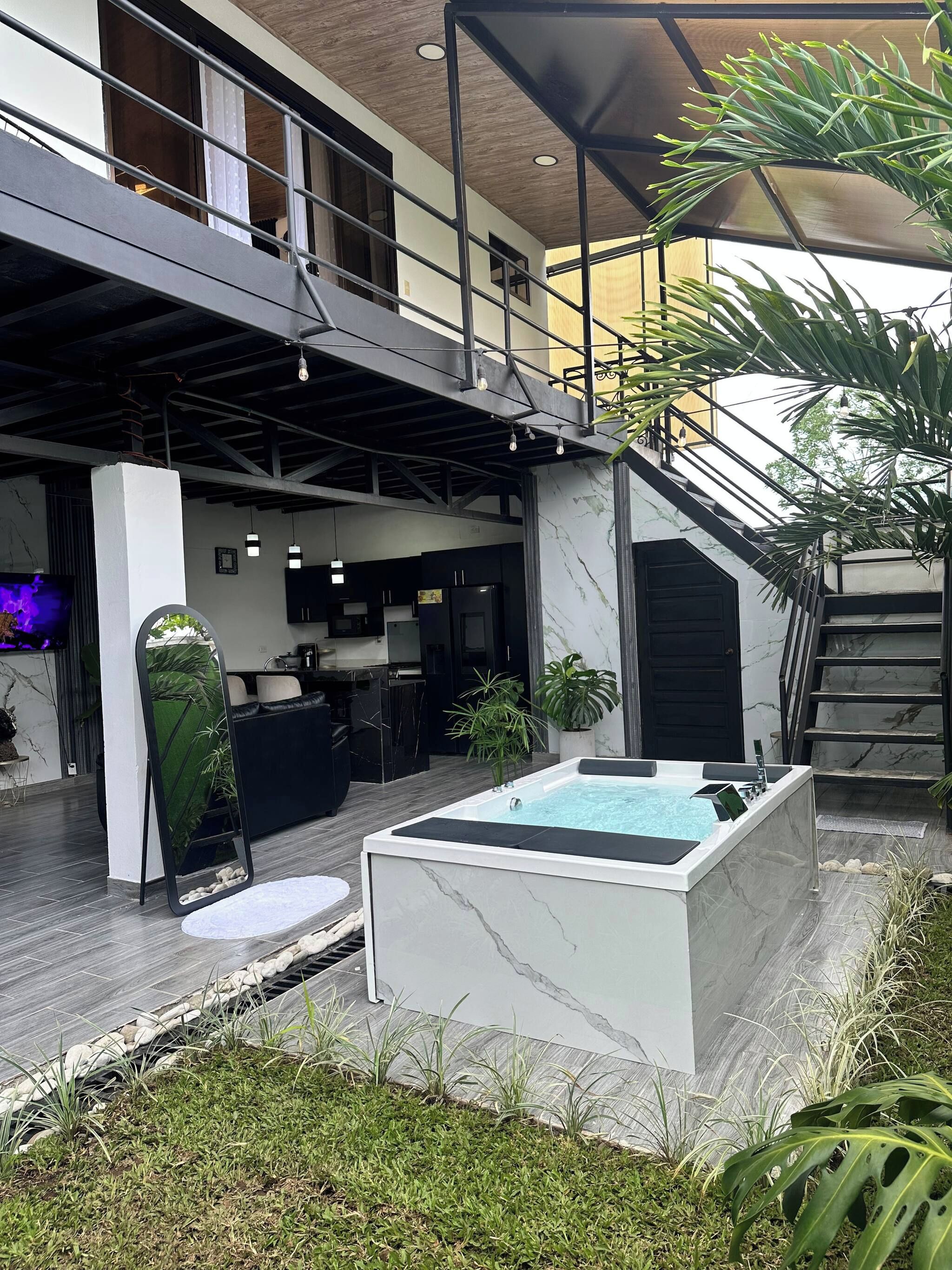 Un espace de vie extérieur moderne doté d’une piscine, d’un escalier et d’un coin cuisine.