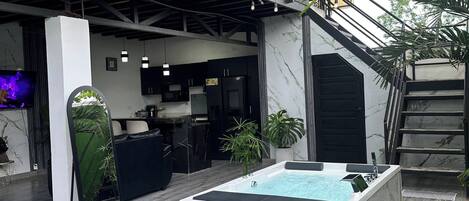 A modern outdoor living space with a pool, a staircase, and a kitchen area.