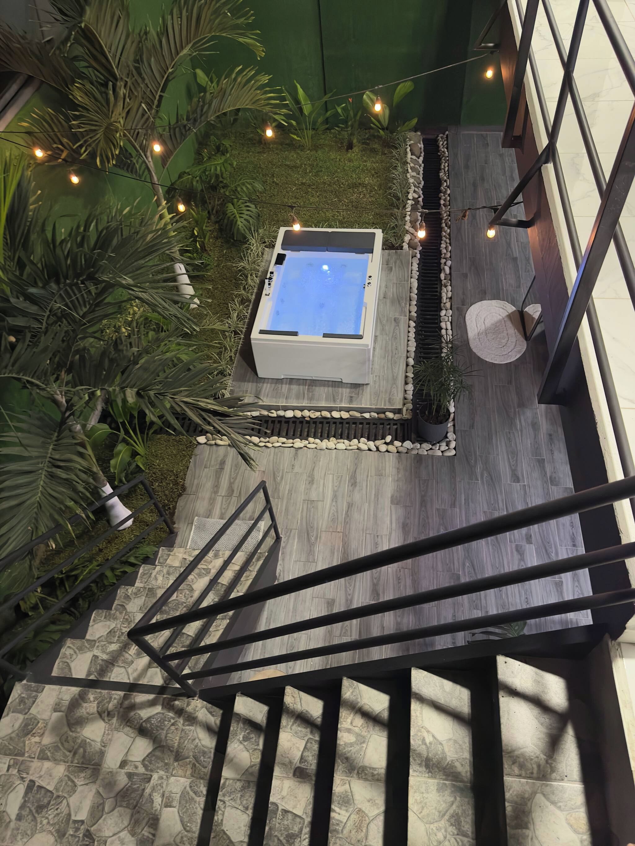 A hot tub surrounded by a stone border, with a staircase leading up to it.