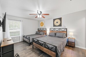 Une chambre avec deux lits, un ventilateur de plafond et des œuvres d’art accrochées aux murs.