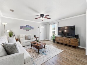 Ein Wohnzimmer mit Sofa, Couchtisch, Fernseher und Deckenventilator.