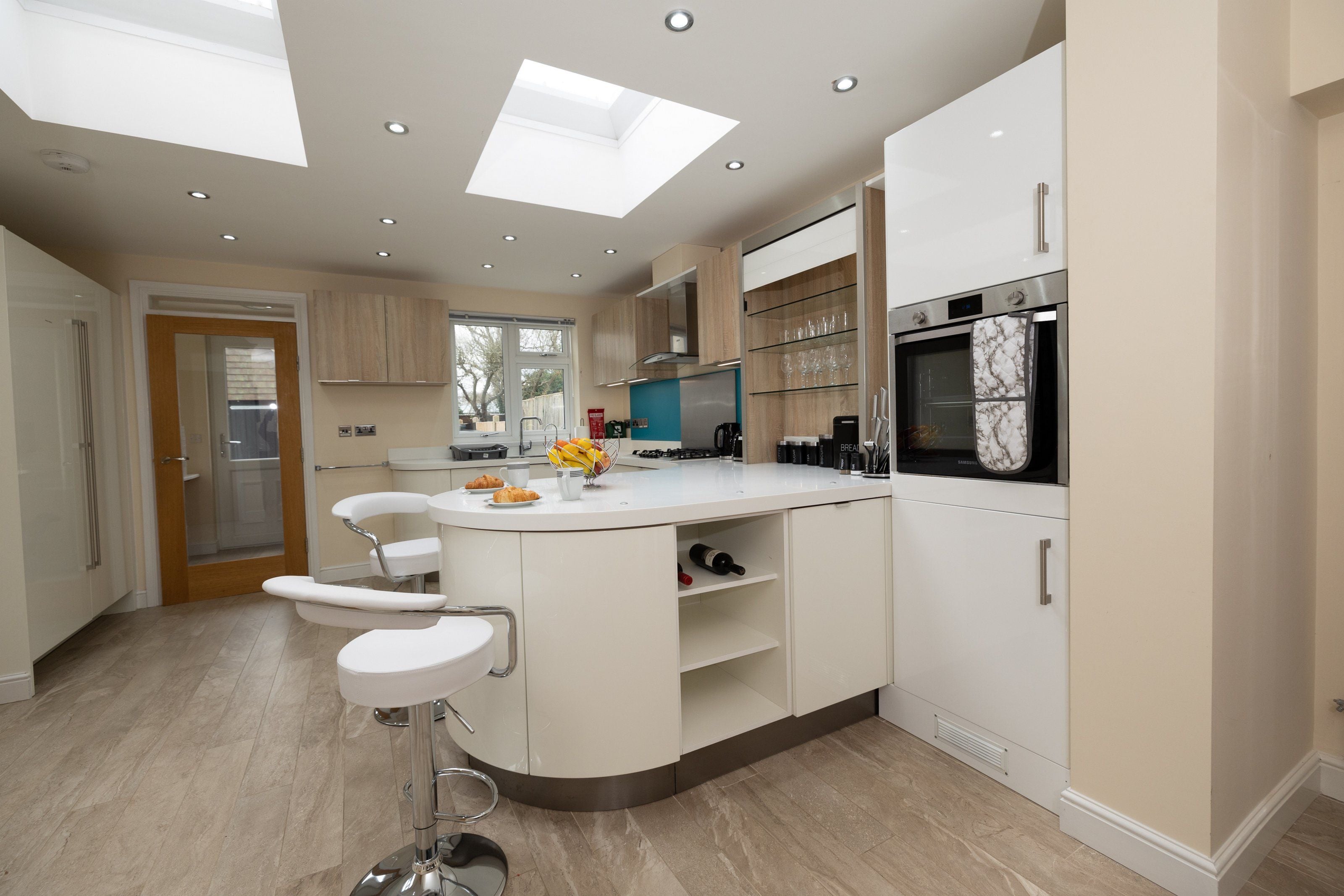 A modern kitchen with a central island, built-in appliances, and a large window.